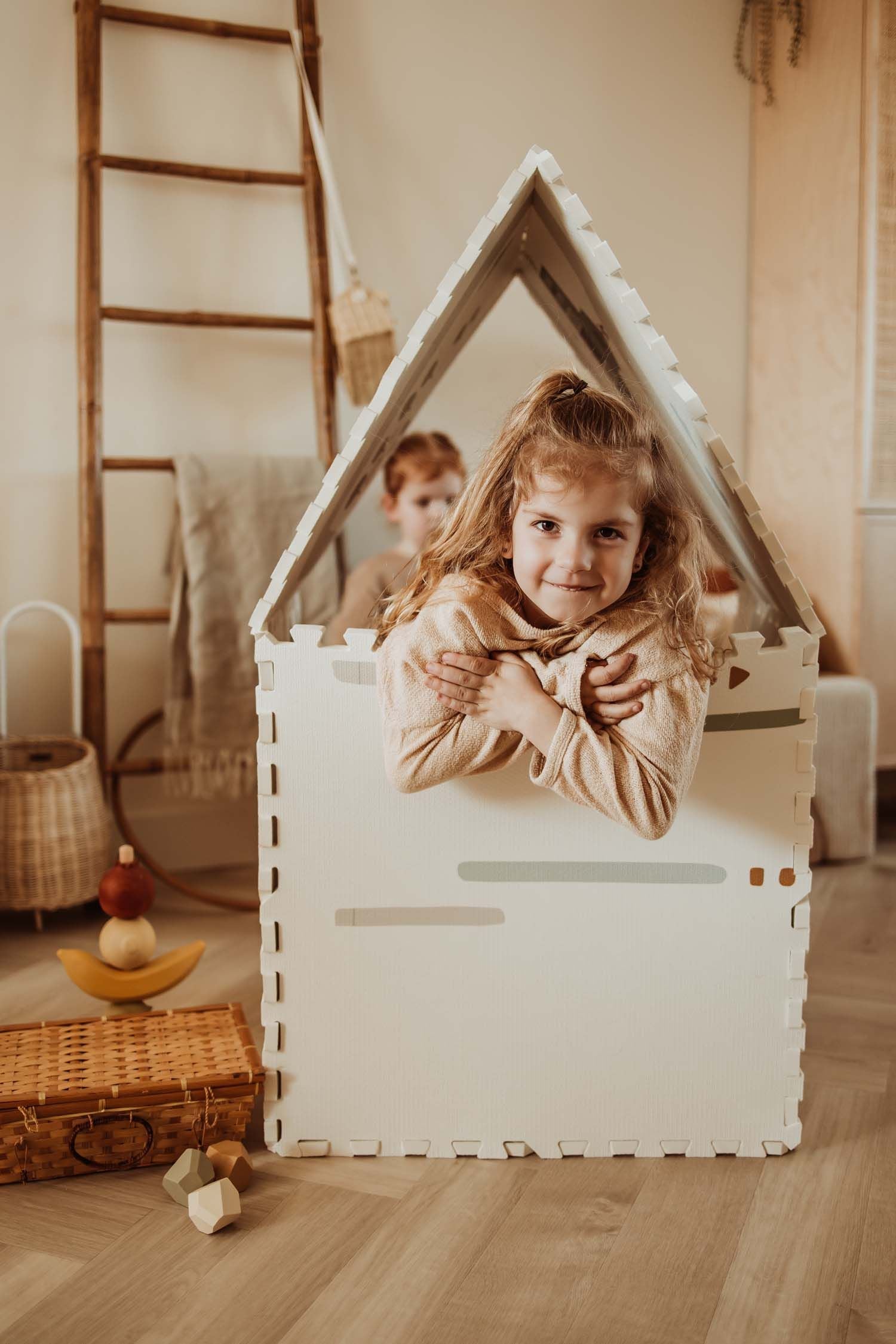 EEVAA farm puzzlemat made into a playhouse, print of icons and stripes, child is sitting in the playhouse
