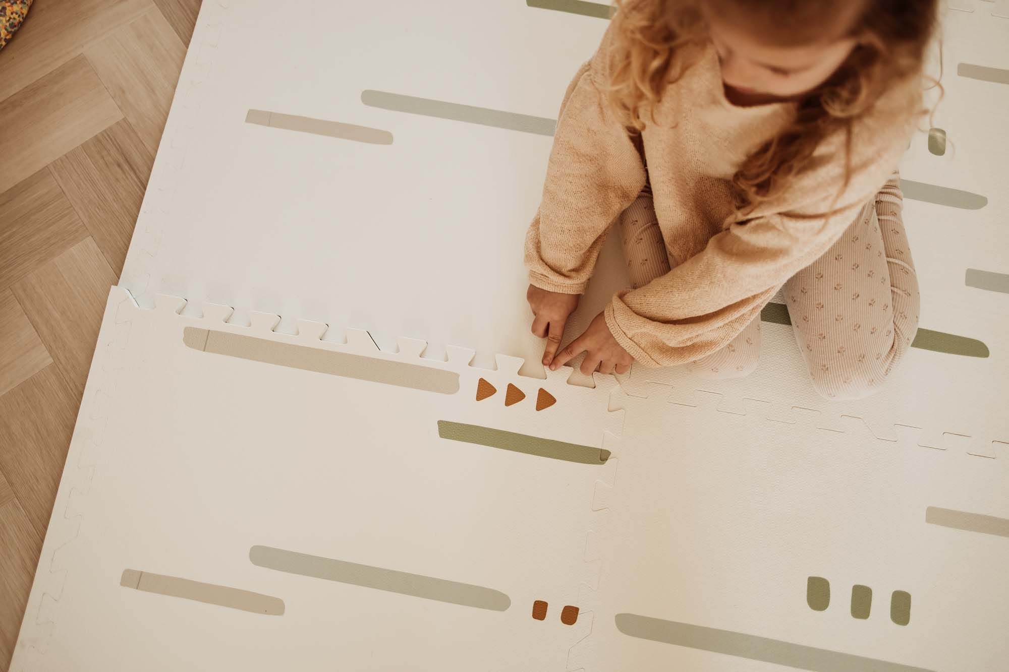 EEVAA farm puzzlemat, backside with stripes and icons, child is creating the puzzle with the pieces