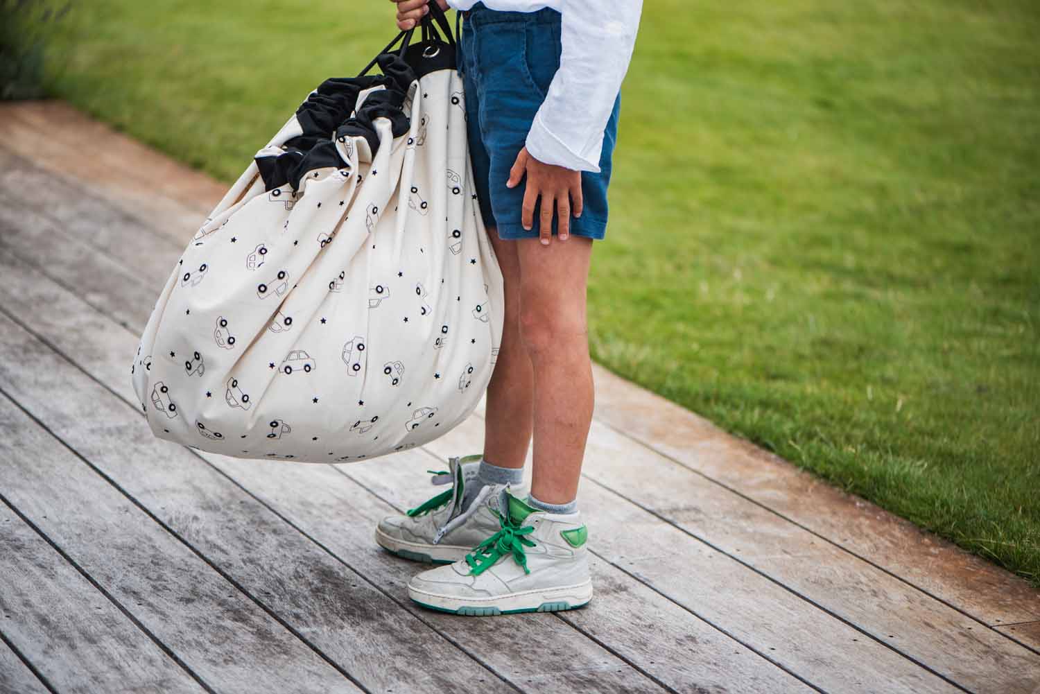 toy storage bag, cars print, child is carrying the bag