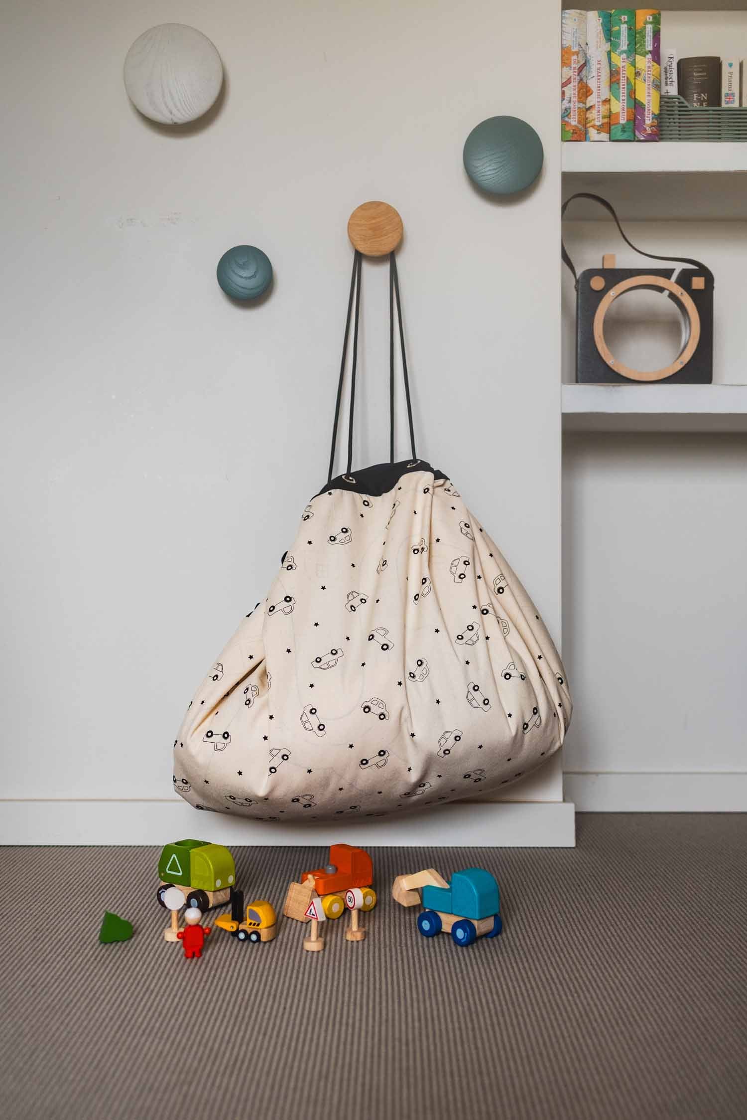 playville toy storage bag, cars print, bag is hanging on coat rack in children room, wooden toys on floor
