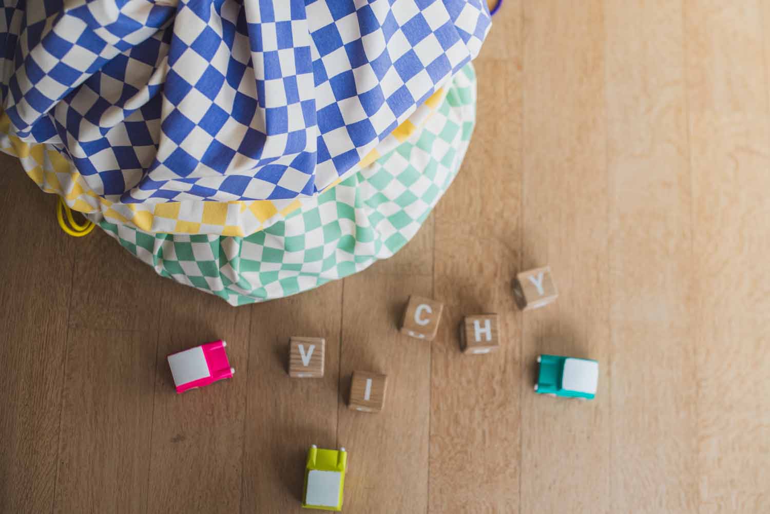 vichy storage bags, all colors, piled on top of each other, wooden blocks and toy cars
