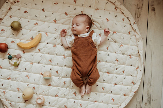 rabbit soft organic babymat, open on floor, little baby is sleeping on the mat, wooden fruit toys