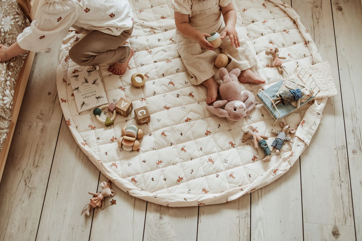 rabbit soft organic babymat, open on floor, children are playing on the mat with mouse cuddles, wooden blocks and books
