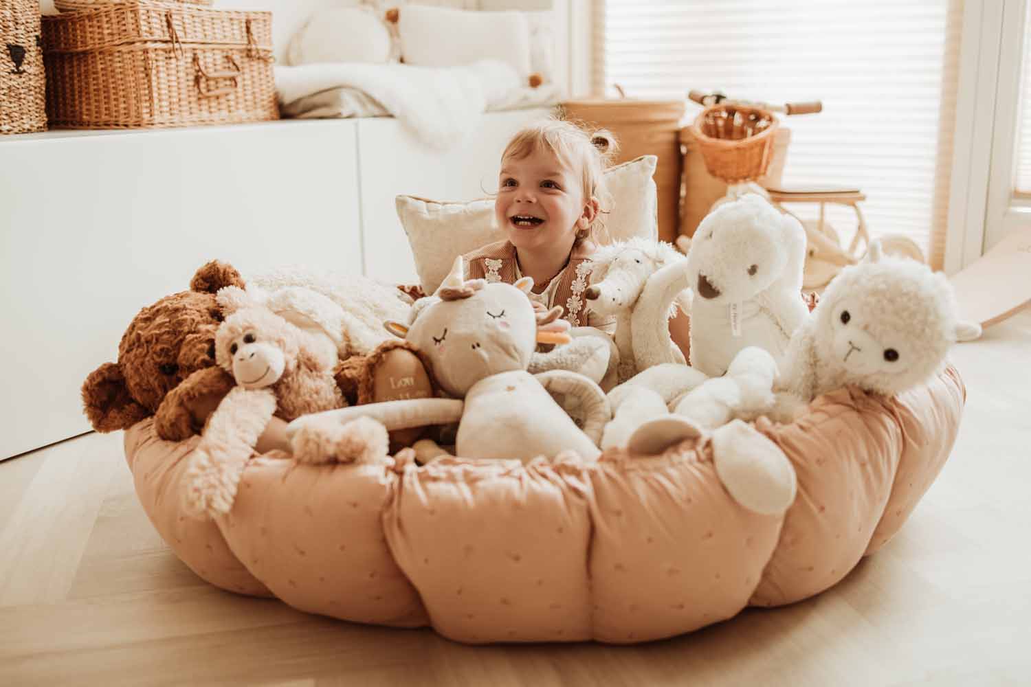 Bloom fleuri organic babymat, child sitting in crib between lots of cuddles