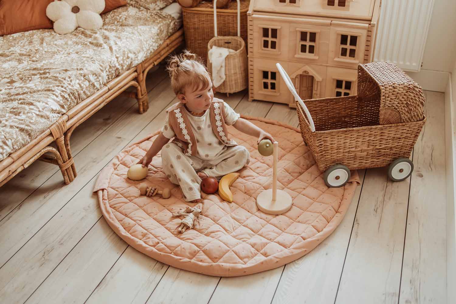Fleuri organic babymat, open on floor in kidsroom, child playing with wooden fruit toys, stroller, playhouse and bed