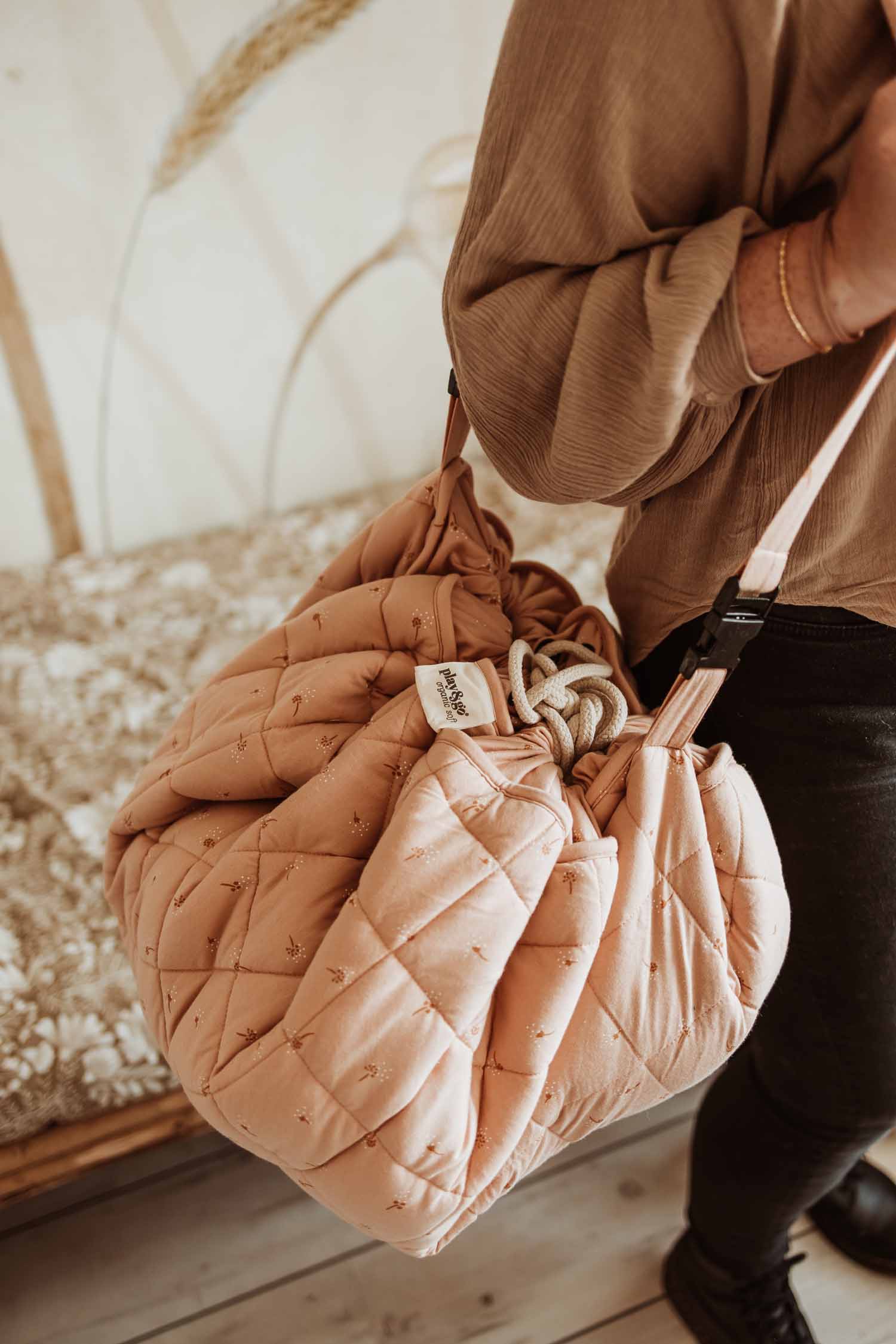 Fleuri organic babymat, person is carrying the closed back with shoulder strap