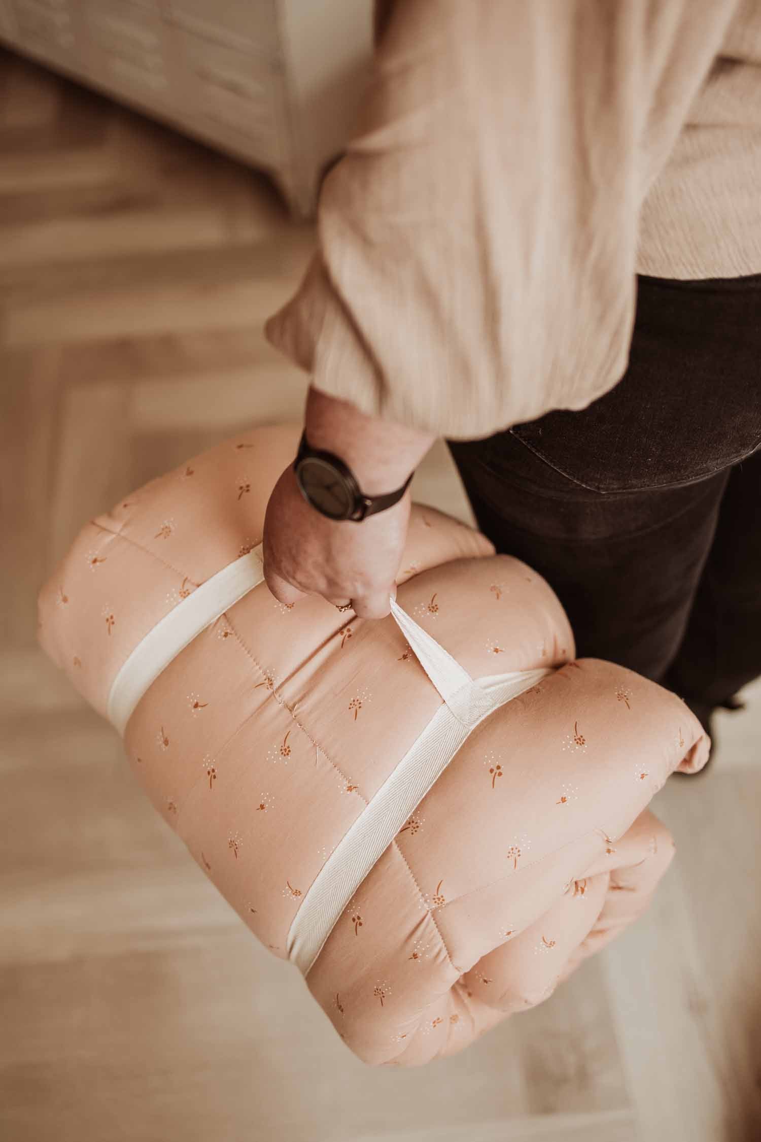 Fleuri organic babymat, person is carrying the closed mat