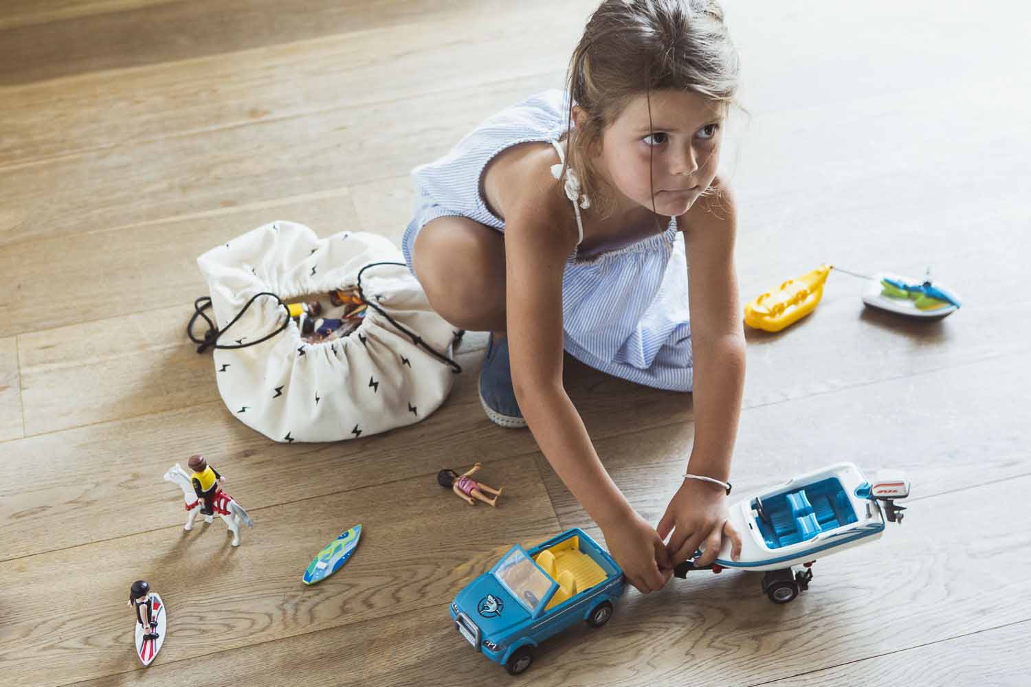 thunderstrike mini toy storage bag, bag on floor, playing girl next to bag and toys