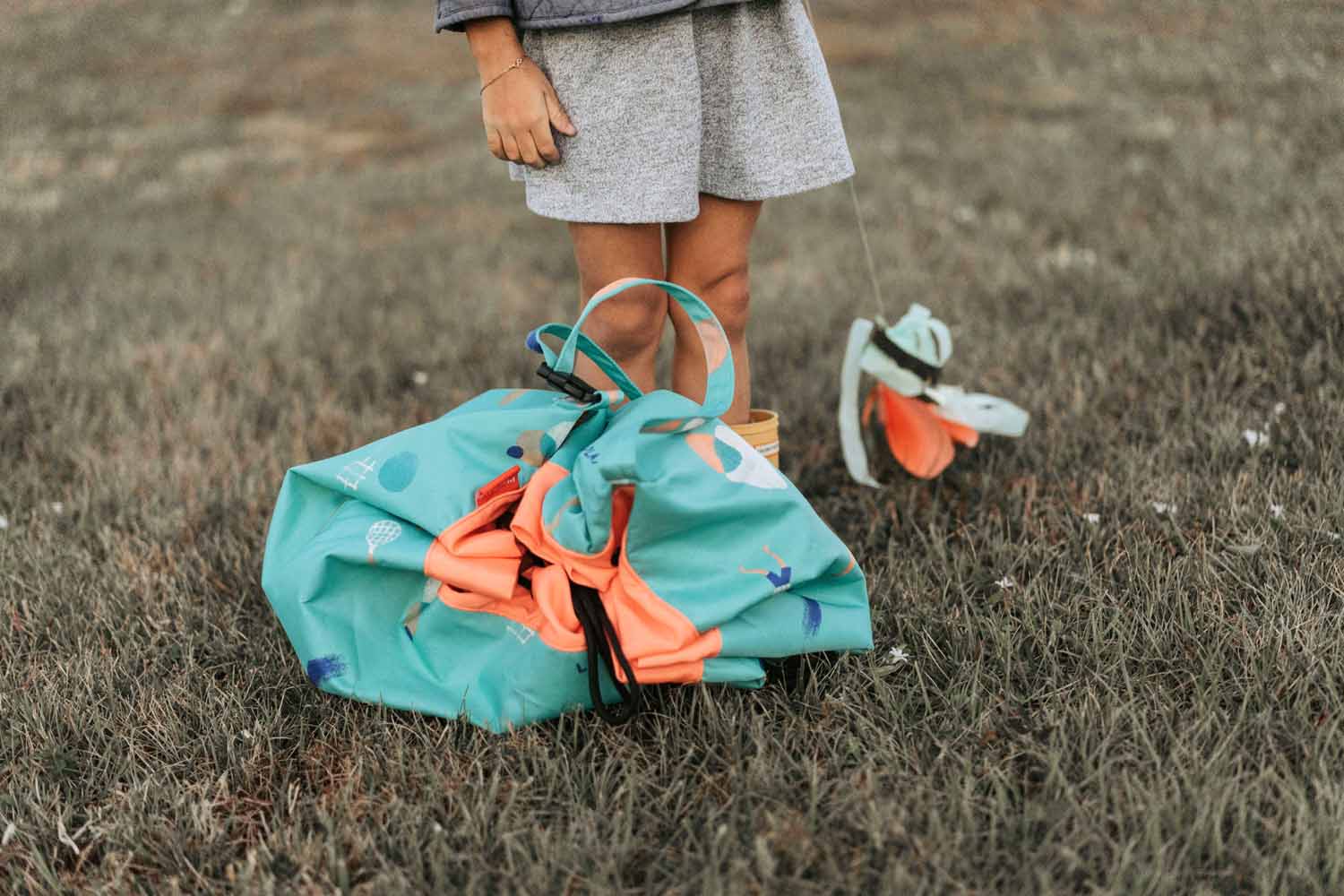 outdoor play storage bag, closed, bag in garden, next to child