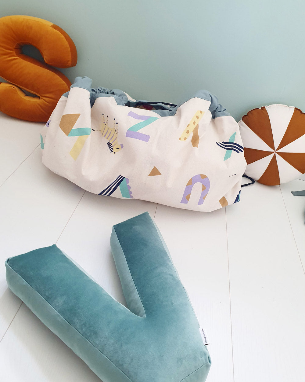 veggie numbers storage bag, closed on floor between pillows S, V and round pillow