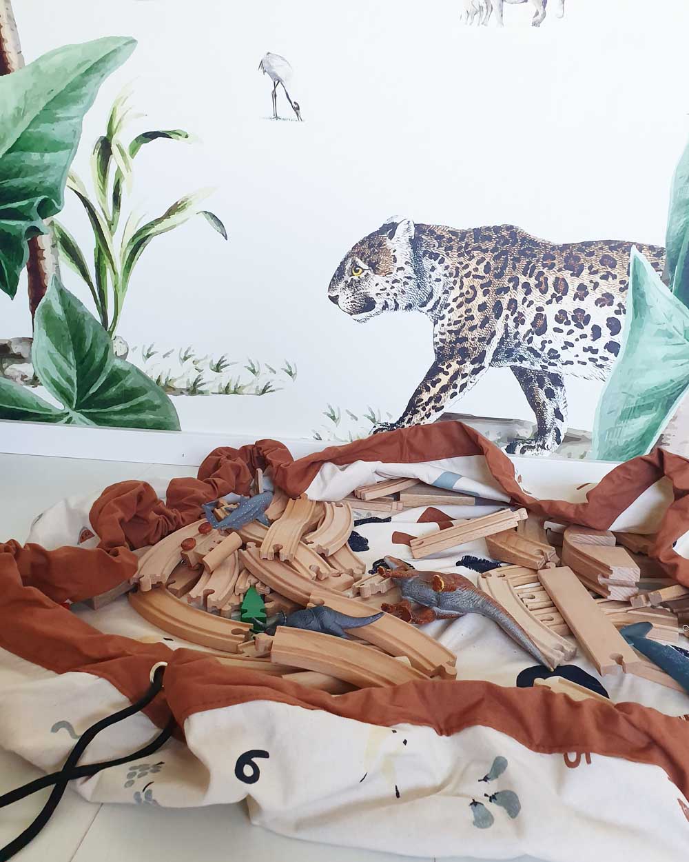 veggie numbers storage bag, open of floor, filled with wooden rails for train, tiger wall paper