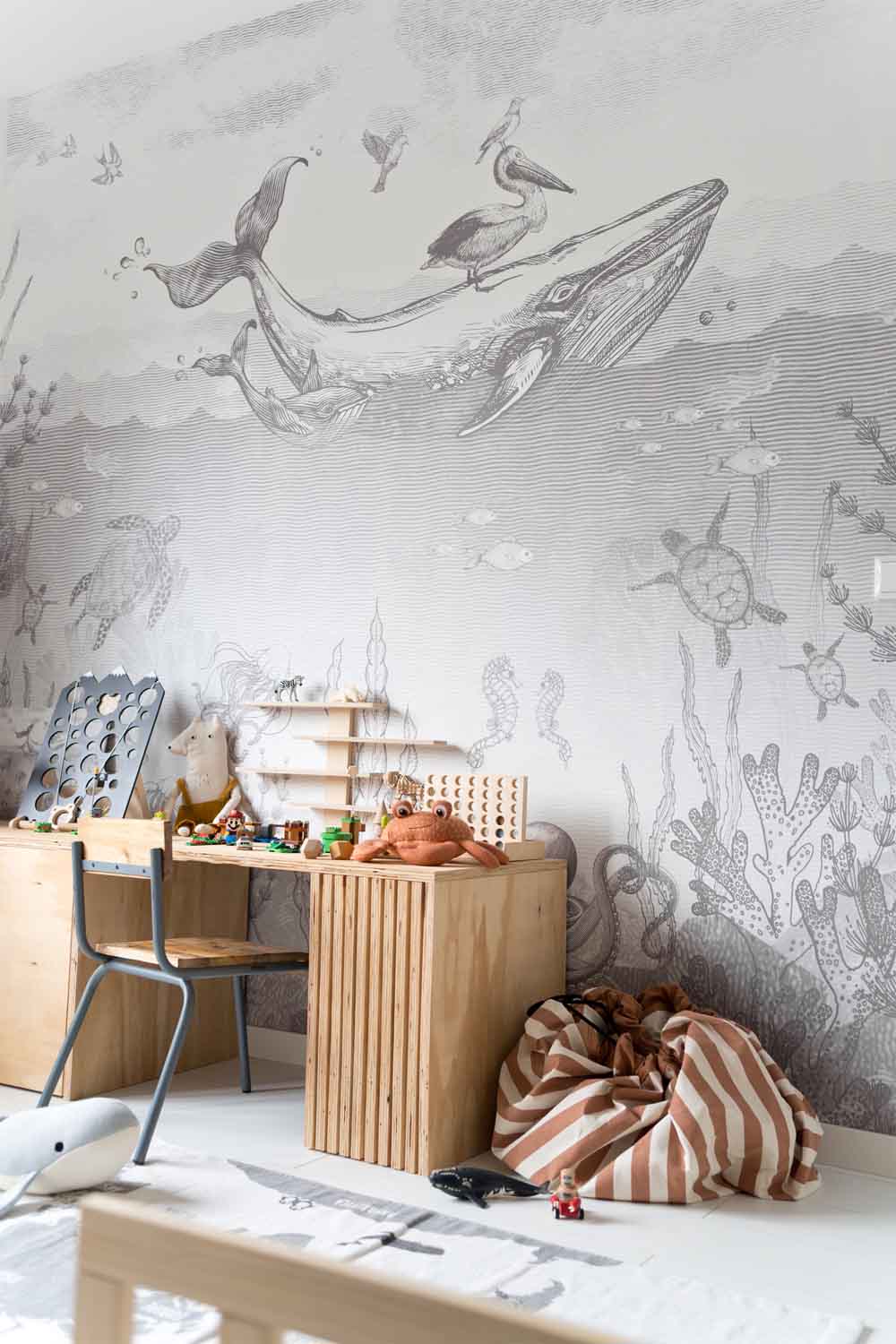 Stripes brown toy storage bag and play mat, standing next to wooden office in kidsroom, whale wall paper in black and white