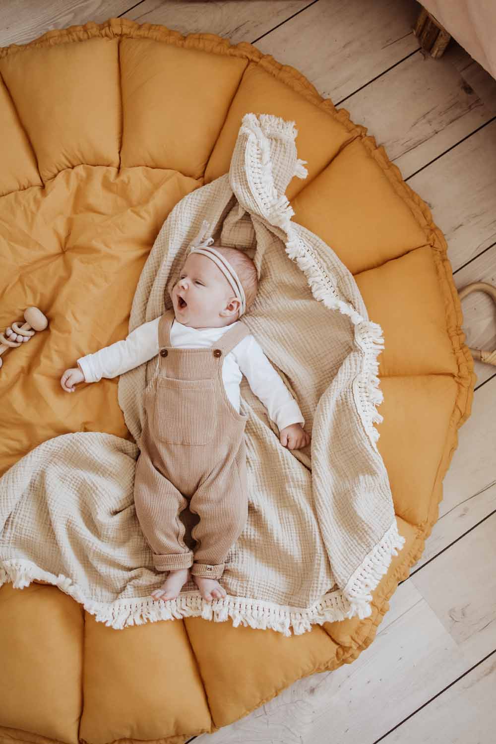Bloom mustard organic babymat, little baby lying on open mat, on little white blanker