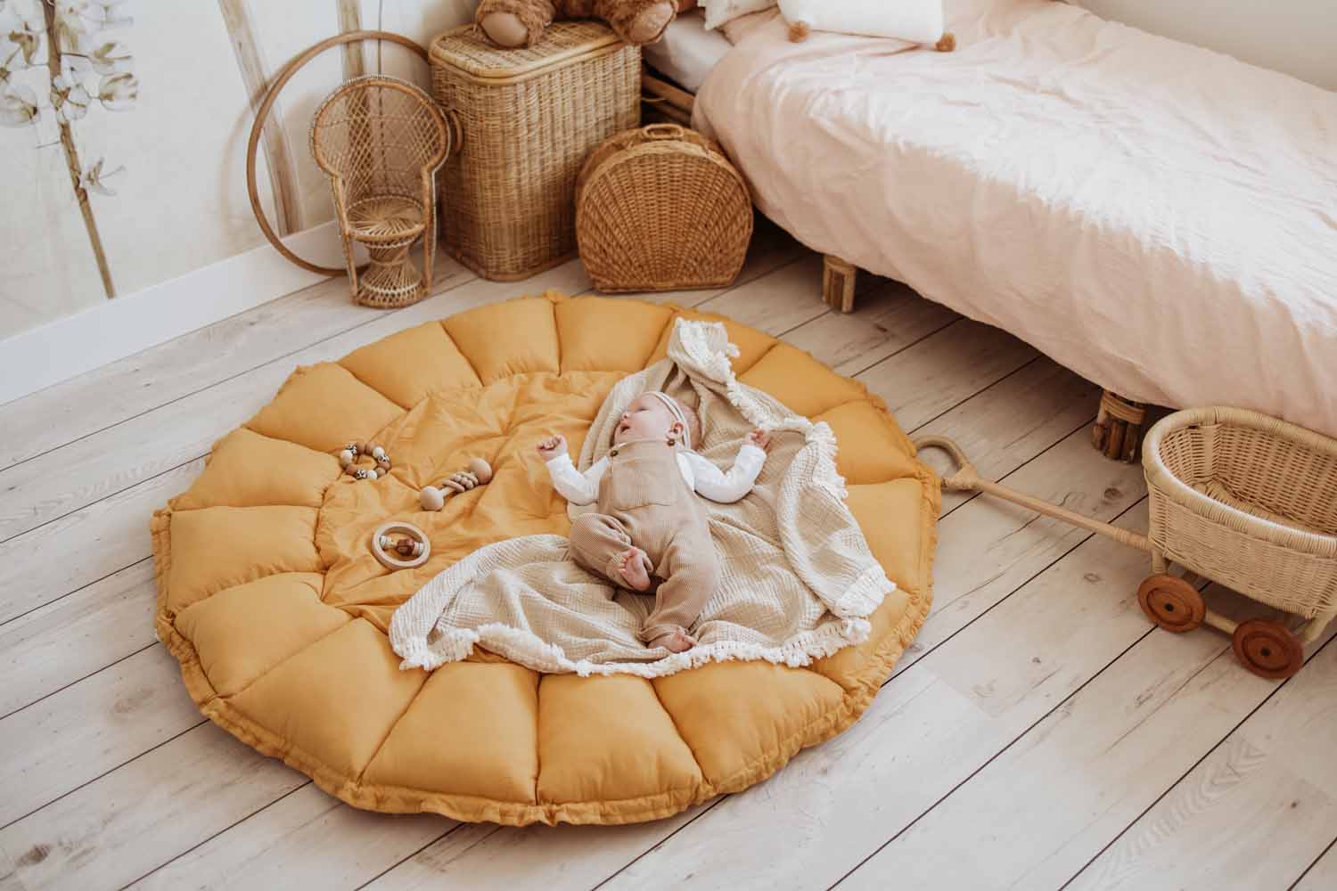 mustard bloom organic babymat, little baby lying on mat in kidsroom, bed in corner of room, wooden basket