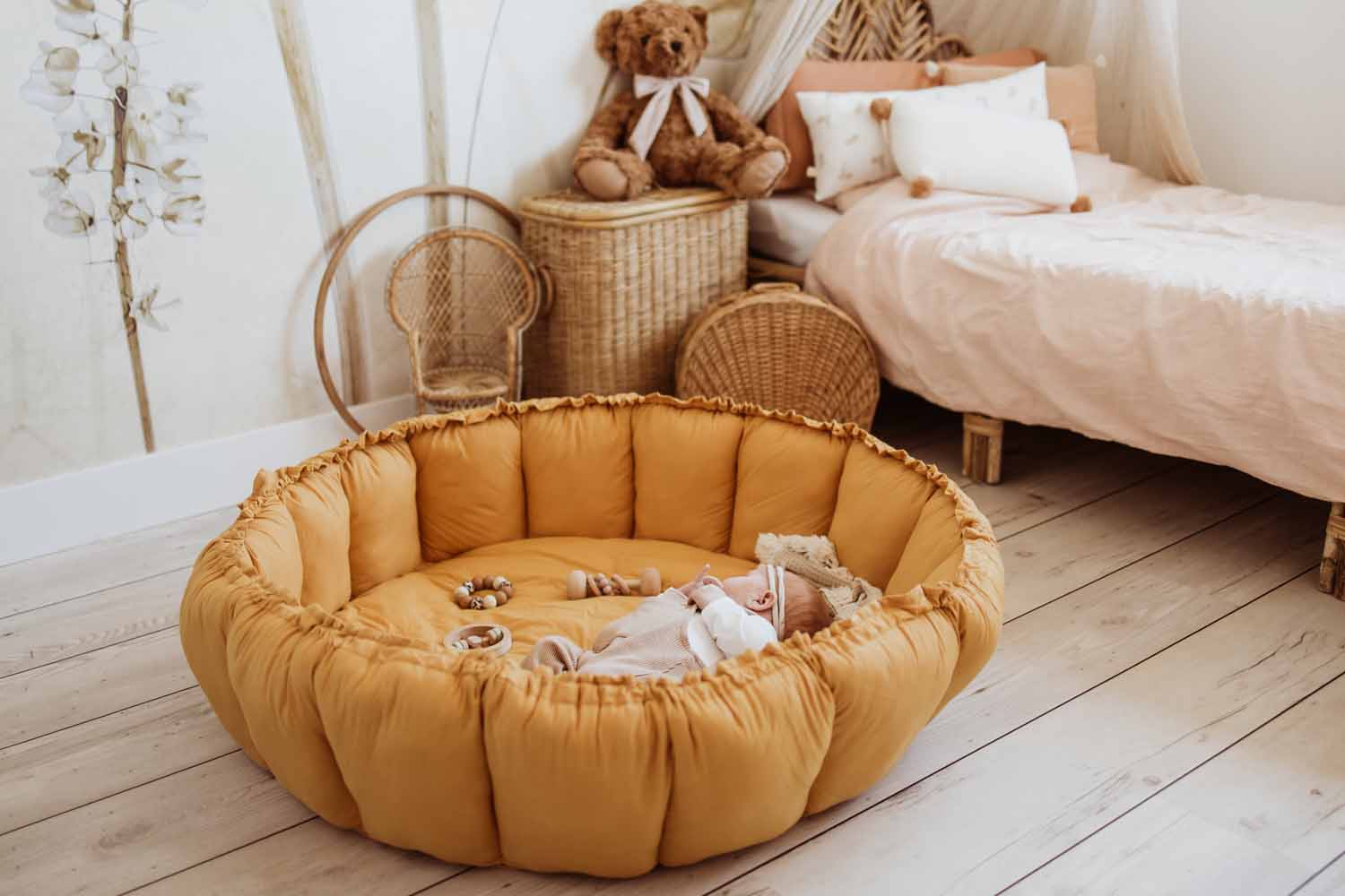 Bloom mustard organic babymat, little baby sleeping on mat, raised edges, bag in kidsroom, next to bed and cuddle bear
