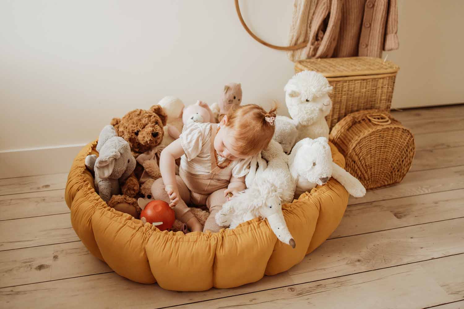 Bloom mustard organic babymat, raised edges, little child sitting on mat between lots of cuddles