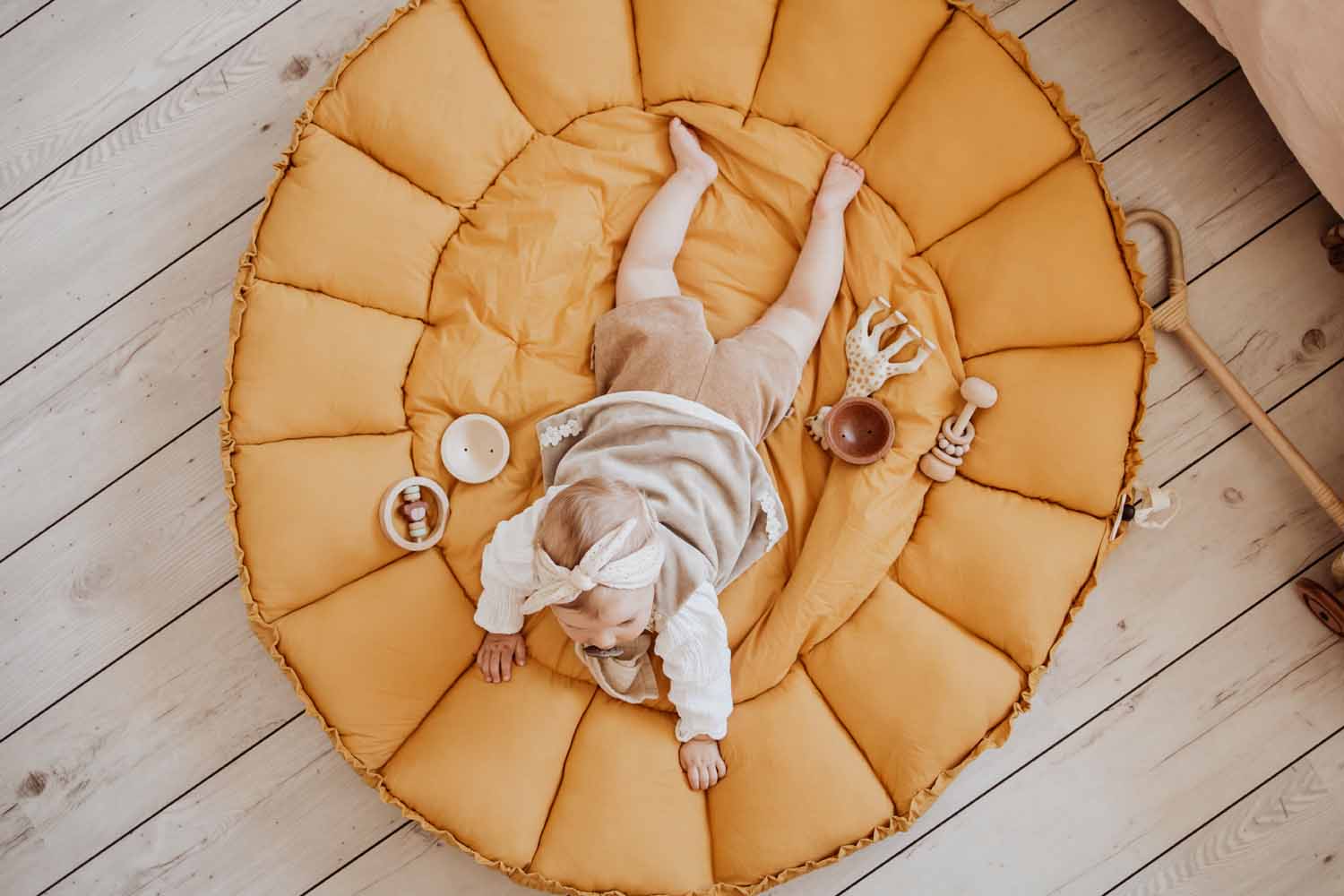 mustard bloom organic baby mat, baby lying on belly on mat, between toys