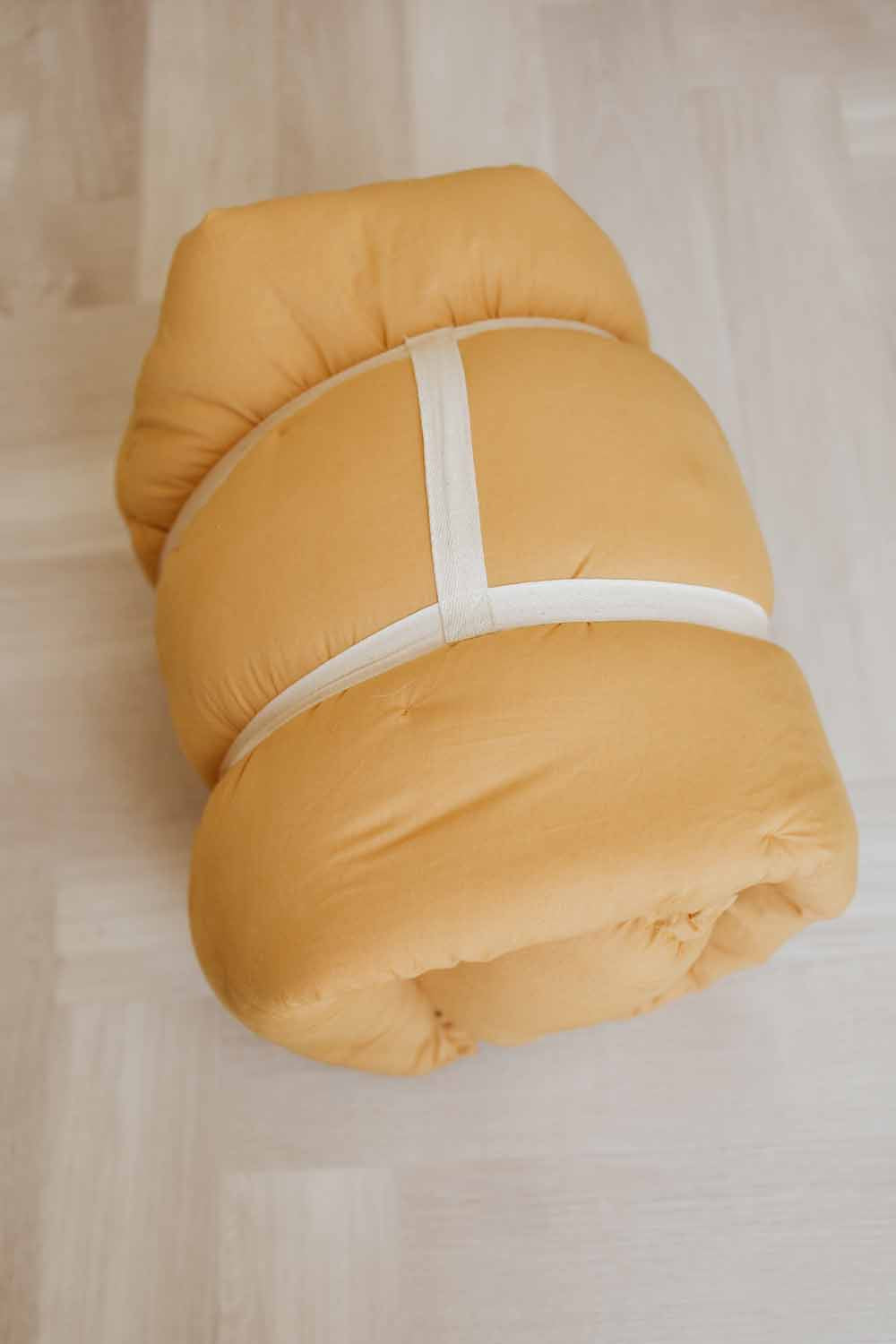 Bloom mustard organic babymat, detail picture of closed bag, wearable in hand