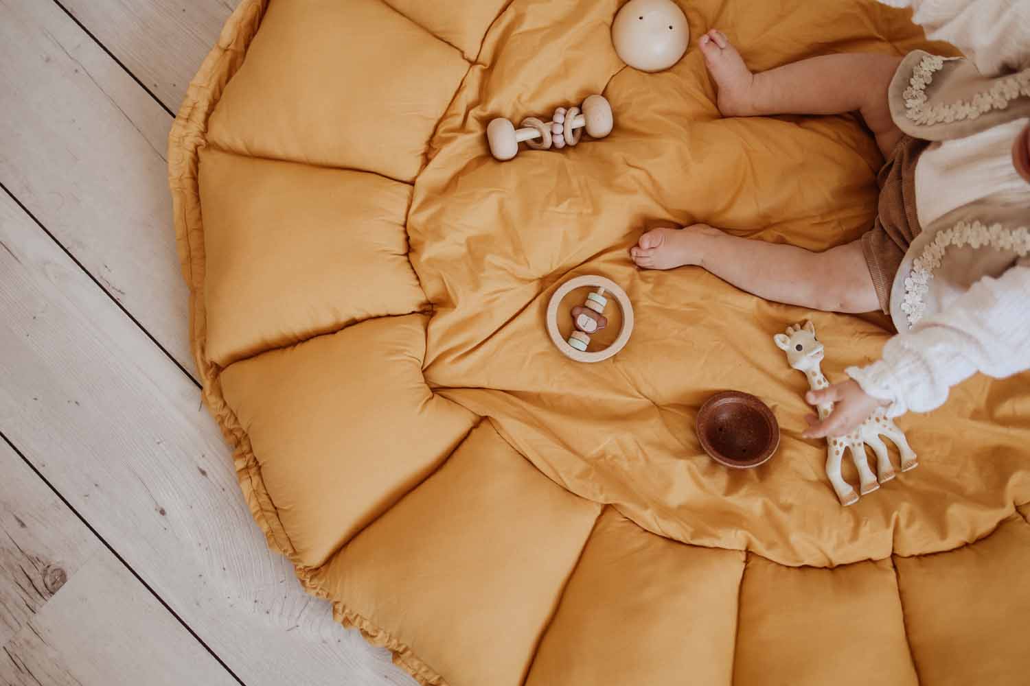 mustard bloom organic baby mat, baby sitting on mat playing with toys, sophie la giraffe