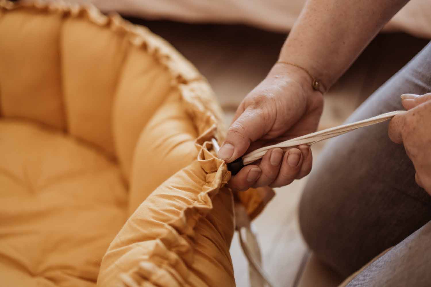 Bloom mustard organic babymat, detail picture of person who is pulling the wropes to raise the edges