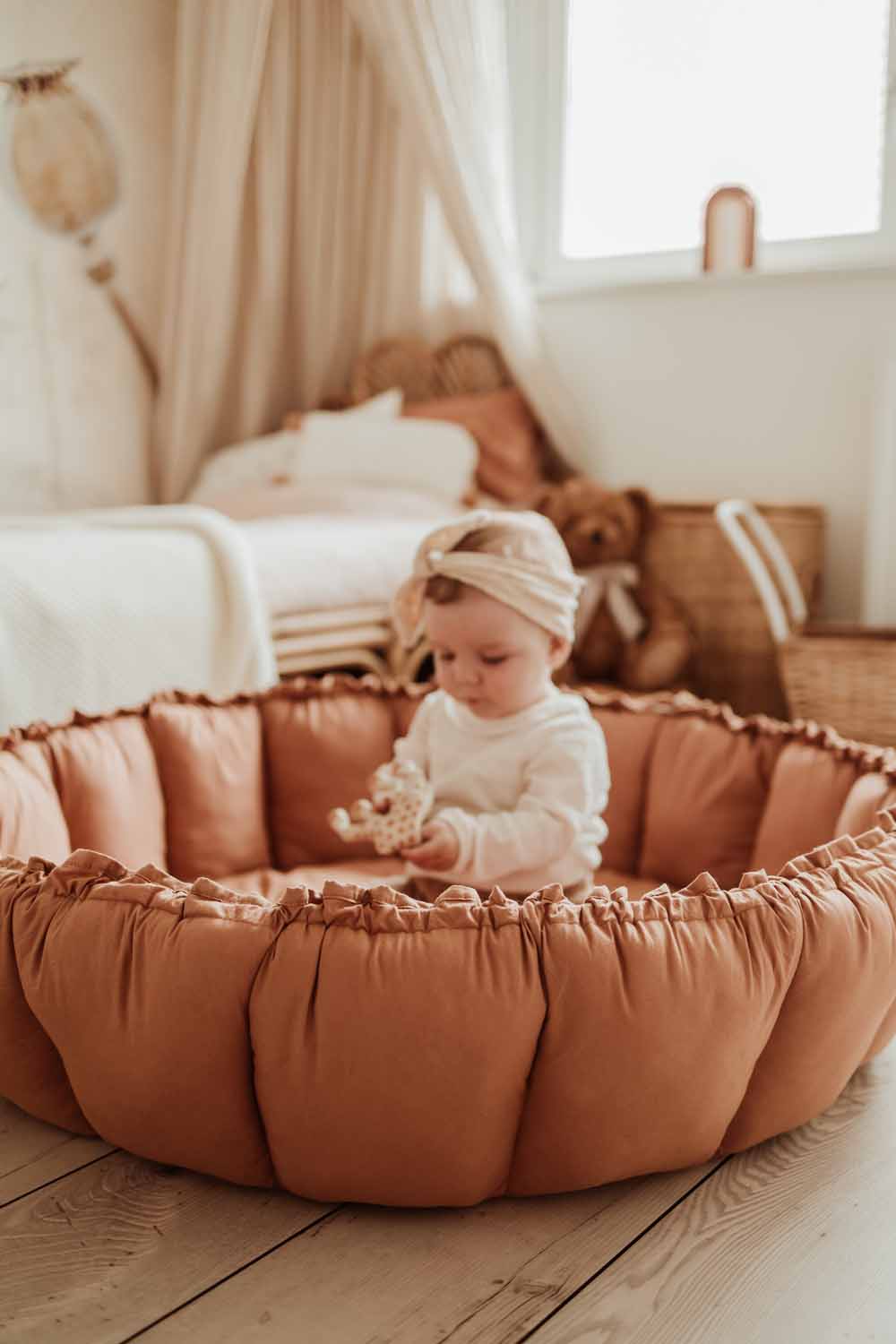 Bloom tawny brown organic babymat, raised edges, child sitting on mat, playing in kidsroom