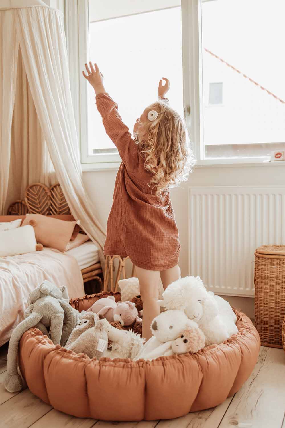 Bloom tawny brown organic babymat, kidsroom, child standing on mat with open arms,mat on floor next to bed, raised edges, filled with cuddles