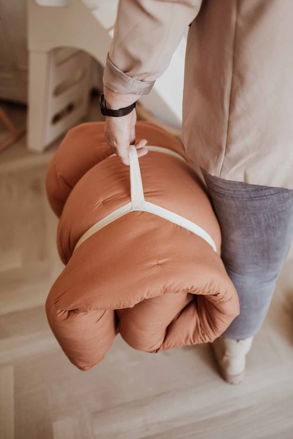 Bloom tawny brown organic babymat, closed mat, person carrying the mat as a bag in hands