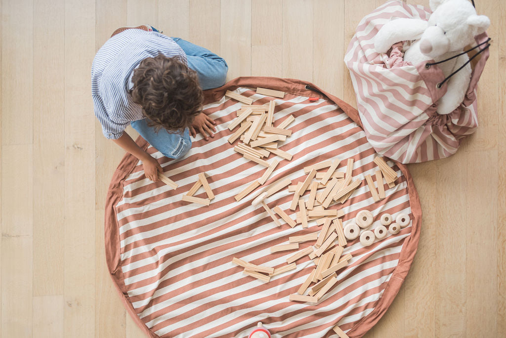 Stripes brown toy storage bag and play mat, child playing with wooden blocks, Stripes New Pink bag filled with cuddle