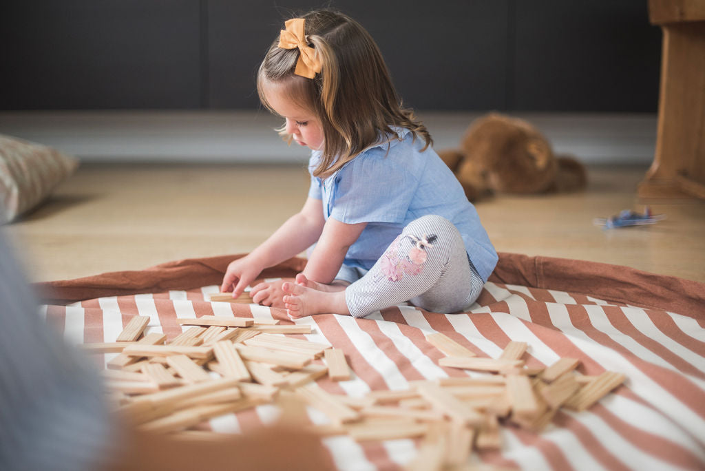 Stripes brown toy storage bag and play mat, child playing with wooden blocks
