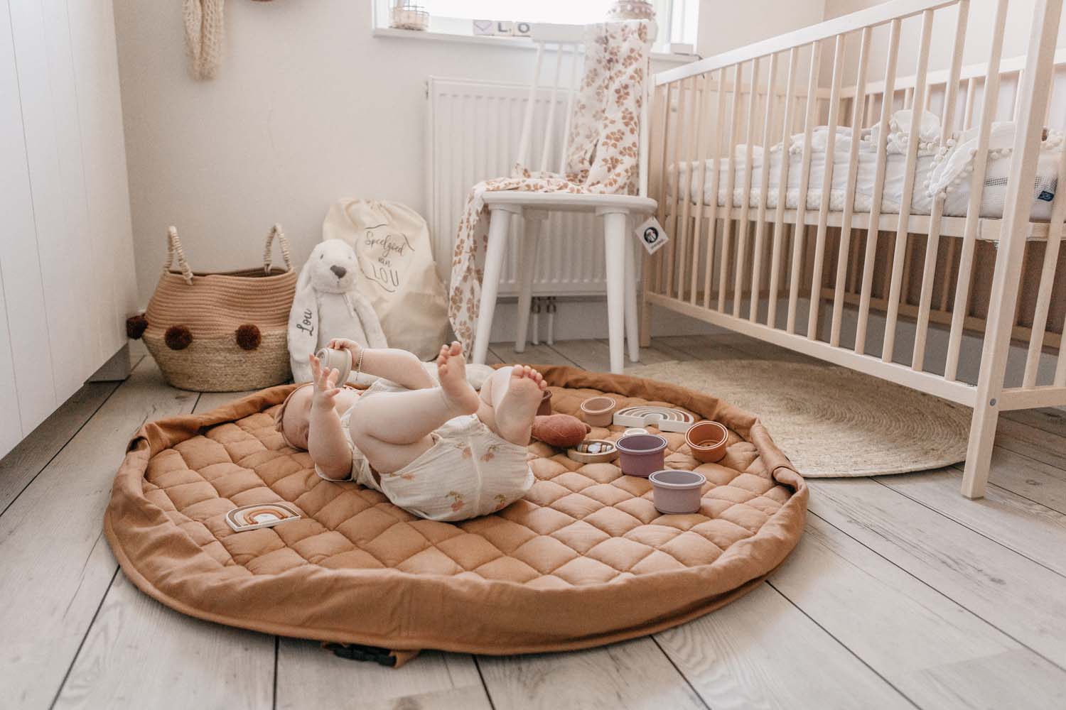 Tawny Brown soft padded baby play mat, baby lying on mat in babys room, lots of toys