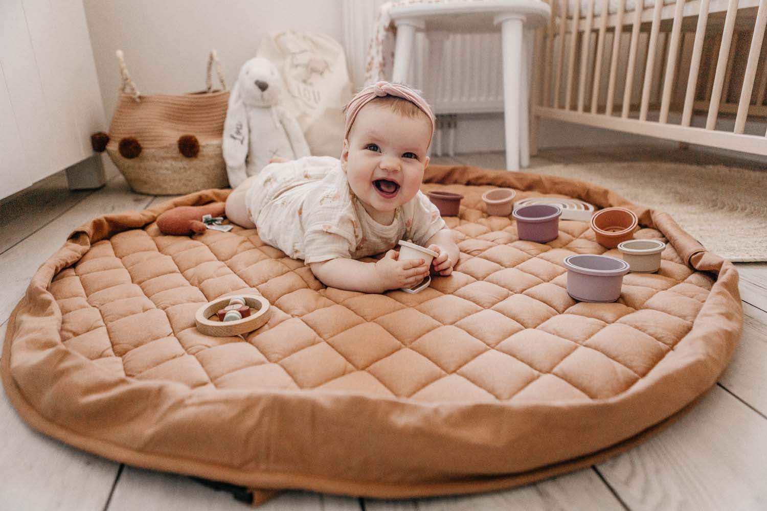 Tawny Brown soft padded baby play mat, baby lying on mat in babys room, lots of toys