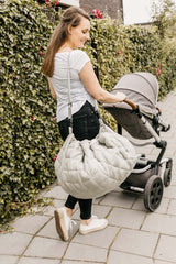 Meadow Green quilted baby storage and diaper bag, woman carrying the bag on her shoulder while pushing the stroller