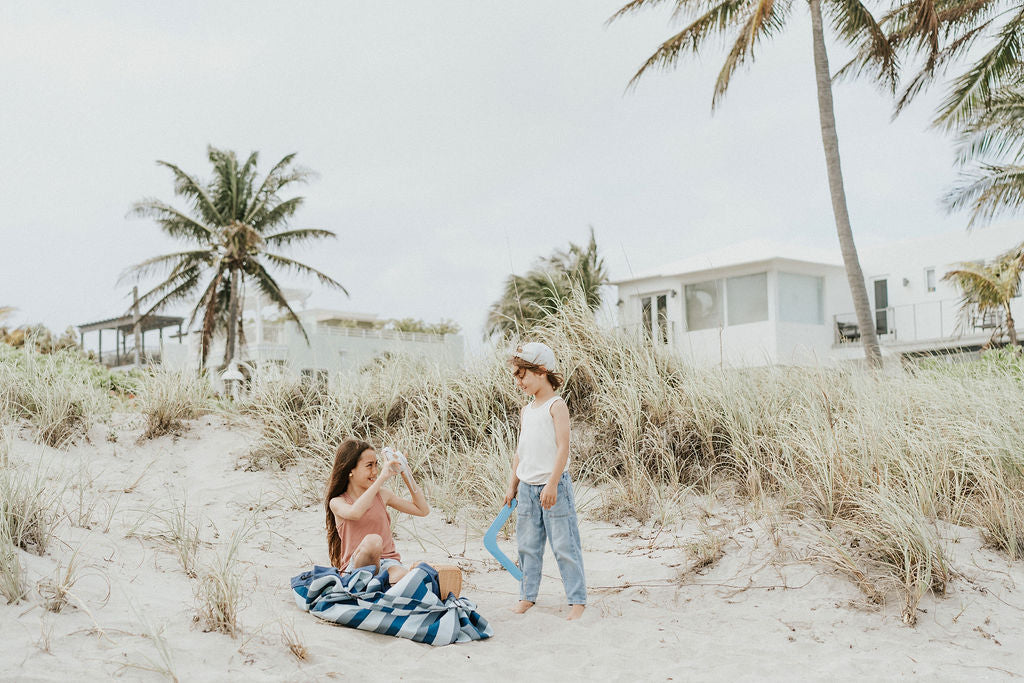 outdoor beach bag blue/green stripes, children sitting on the beach, child holding a boomerang