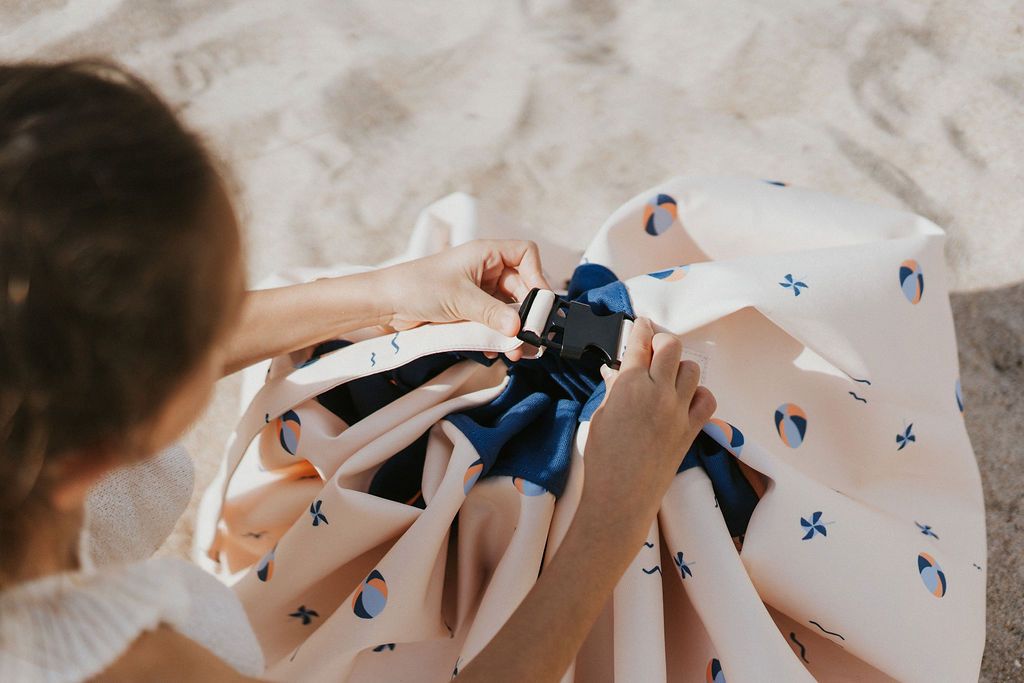 outdoor balloon storage bag and play mat, child closing the bag, standing at the beach