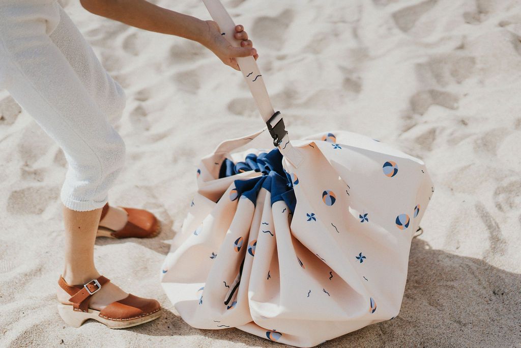 outdoor balloon storage bag and play mat, child closing the bag, standing at the beach