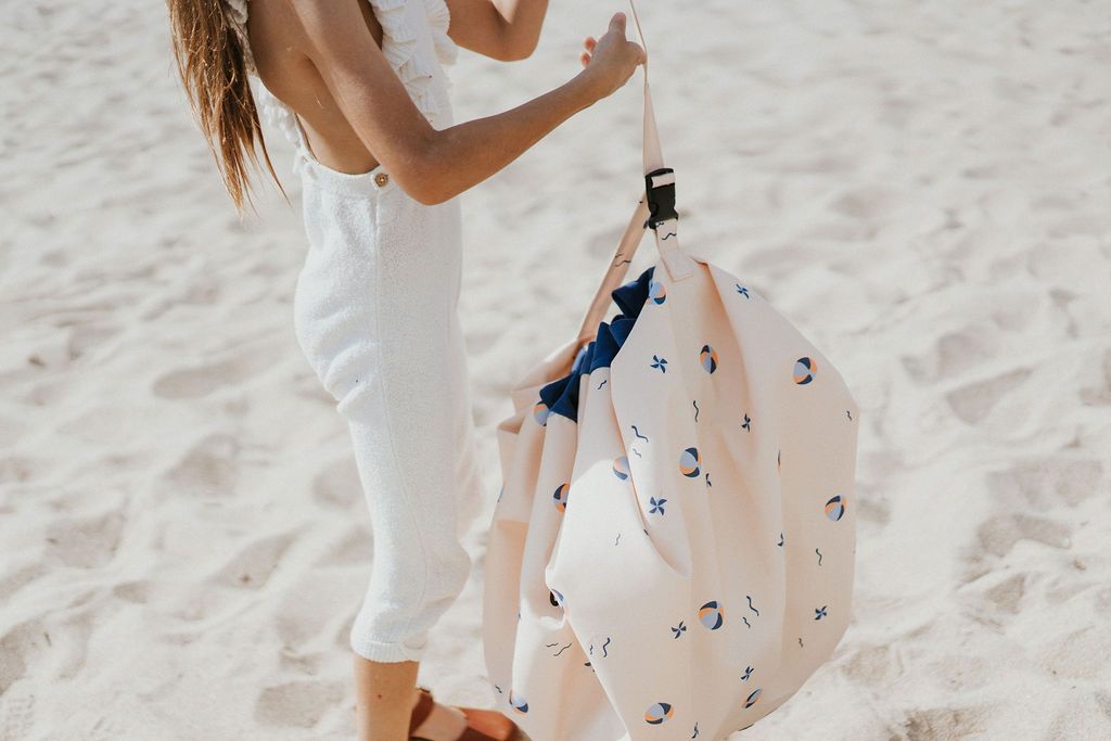 outdoor balloon storage bag and play mat, child carrying the bag, standing at the beach