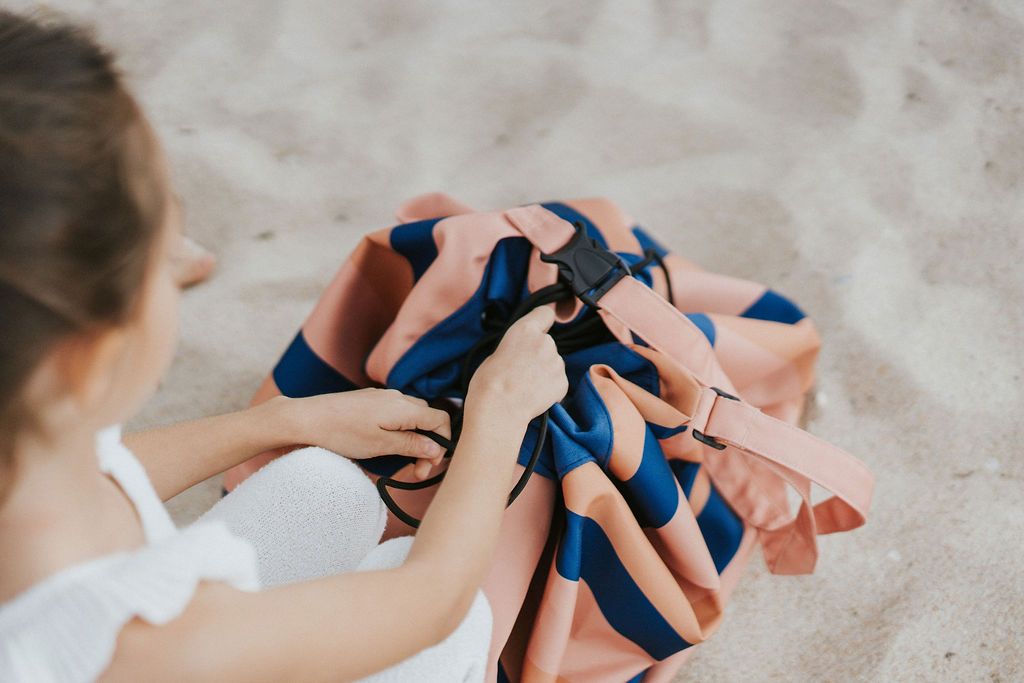 mokka stripes outdoor storage bag, child closing the bag, standing in the sand