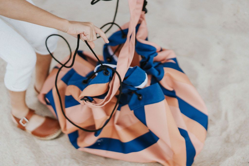 mokka stripes outdoor storage bag, child closing the bag, standing in the sand