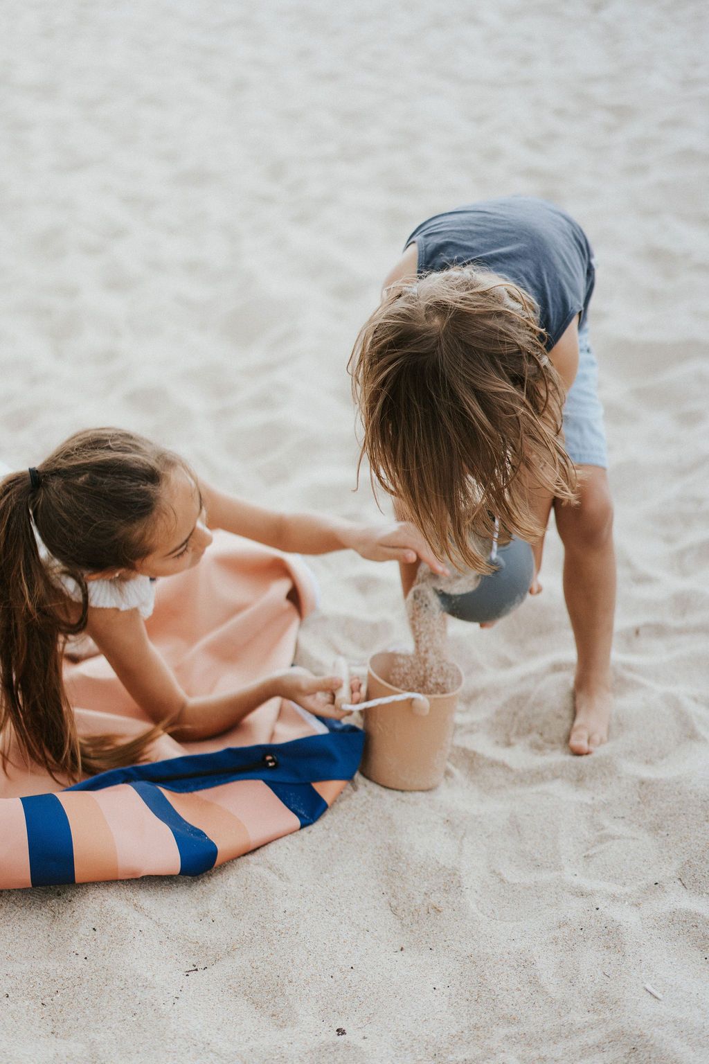 mokka stripes outdoor beach bag, children sitting on the bag in the sand, while playing with beach toys