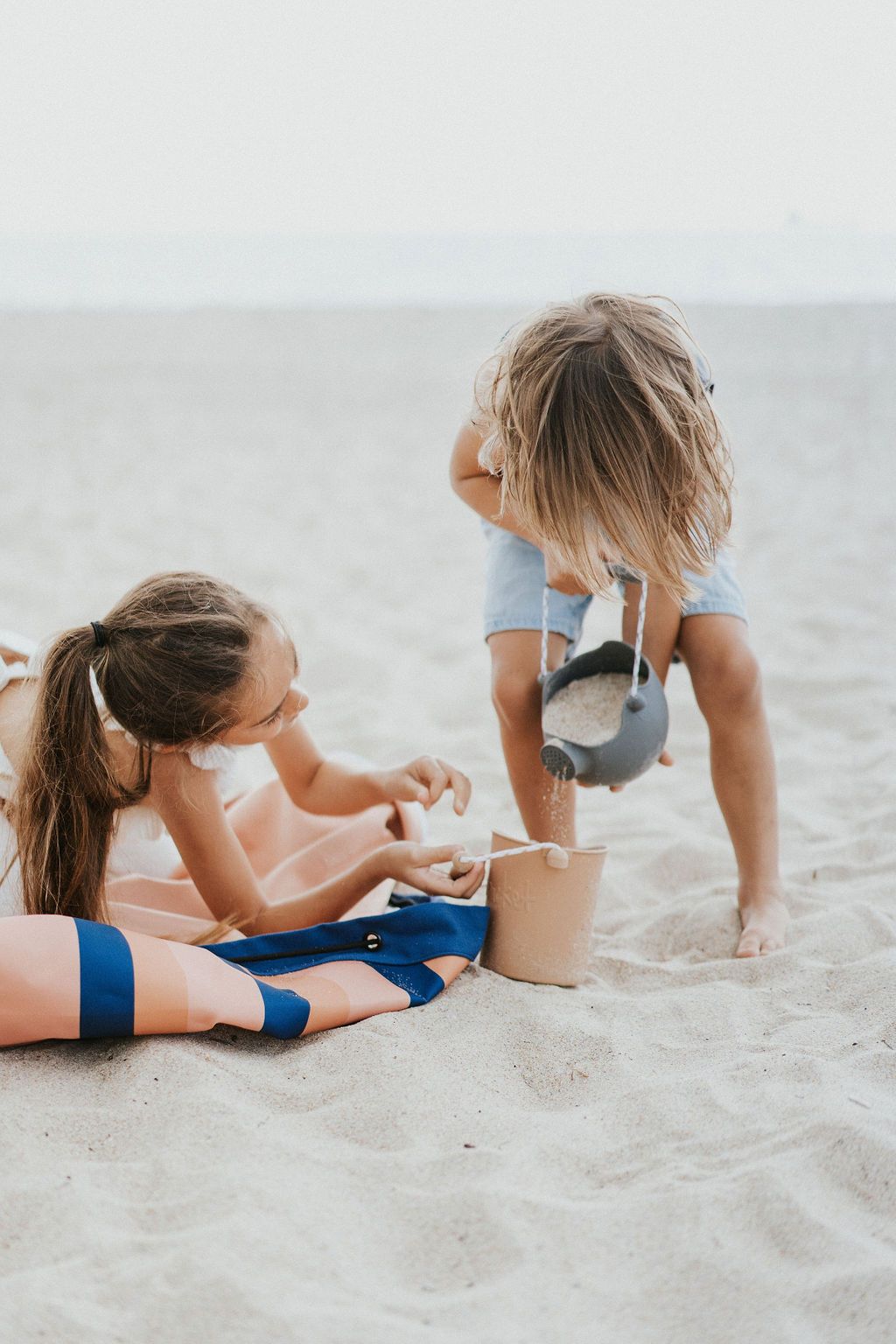 mokka stripes outdoor beach bag, children sitting on the bag in the sand, while playing with beach toys