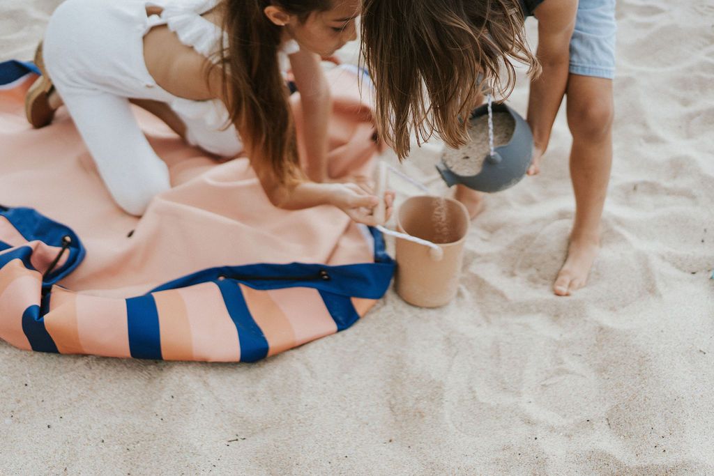 mokka stripes outdoor beach bag, children sitting on the bag in the sand, while playing with beach toys