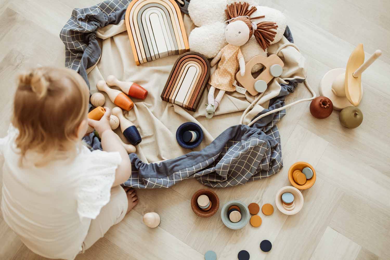 organic storage bag grid blue, open bag on floor, filled with wooden toys, child playing, soft doll