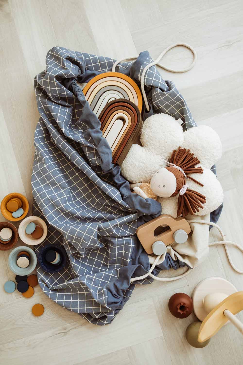 organic storage bag grid blue, bag on floor, filled with wooden toys and doll