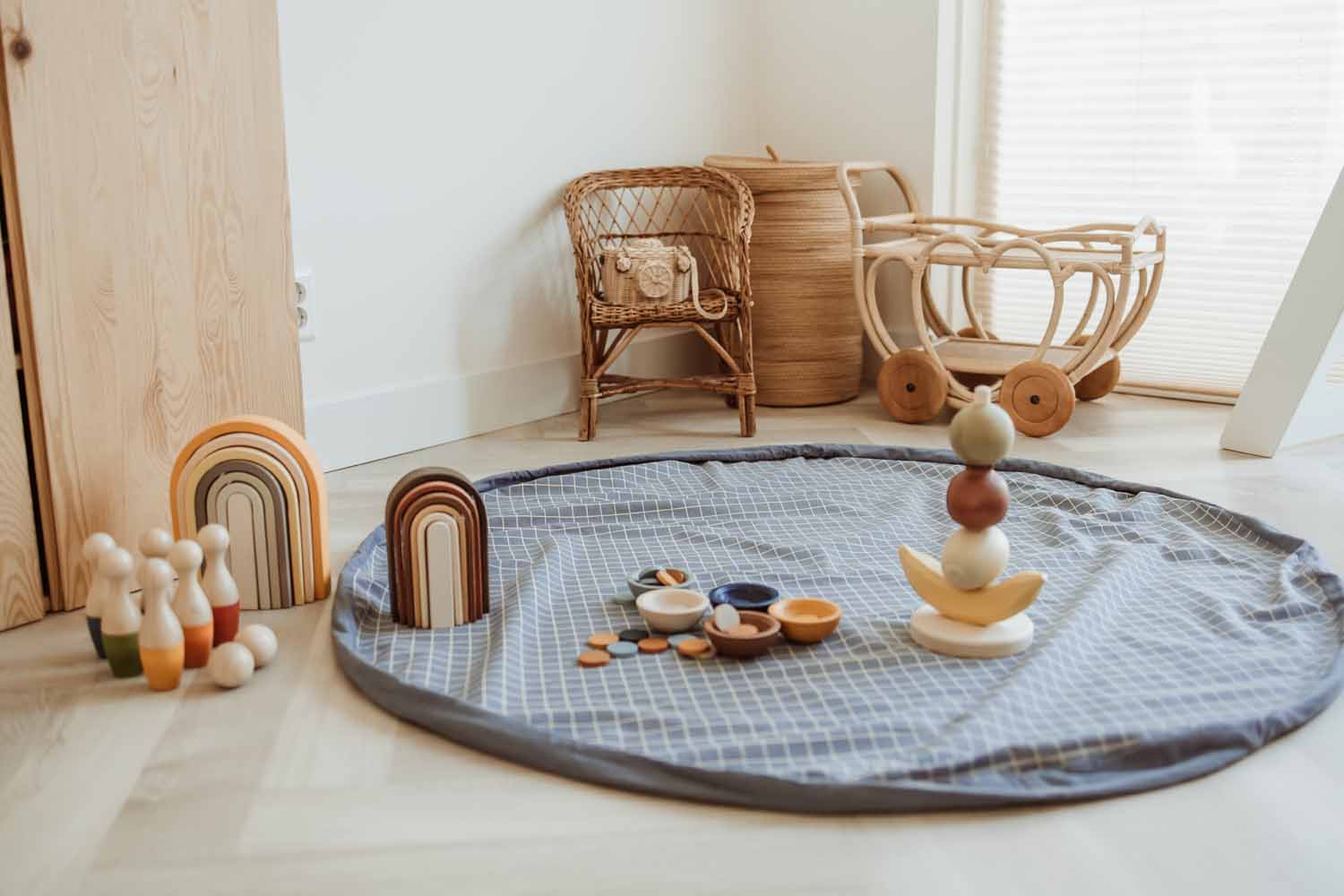 open organic grid blue storage bag, on floor in kidsroom, wooden toys, wicker chair and baby carriage