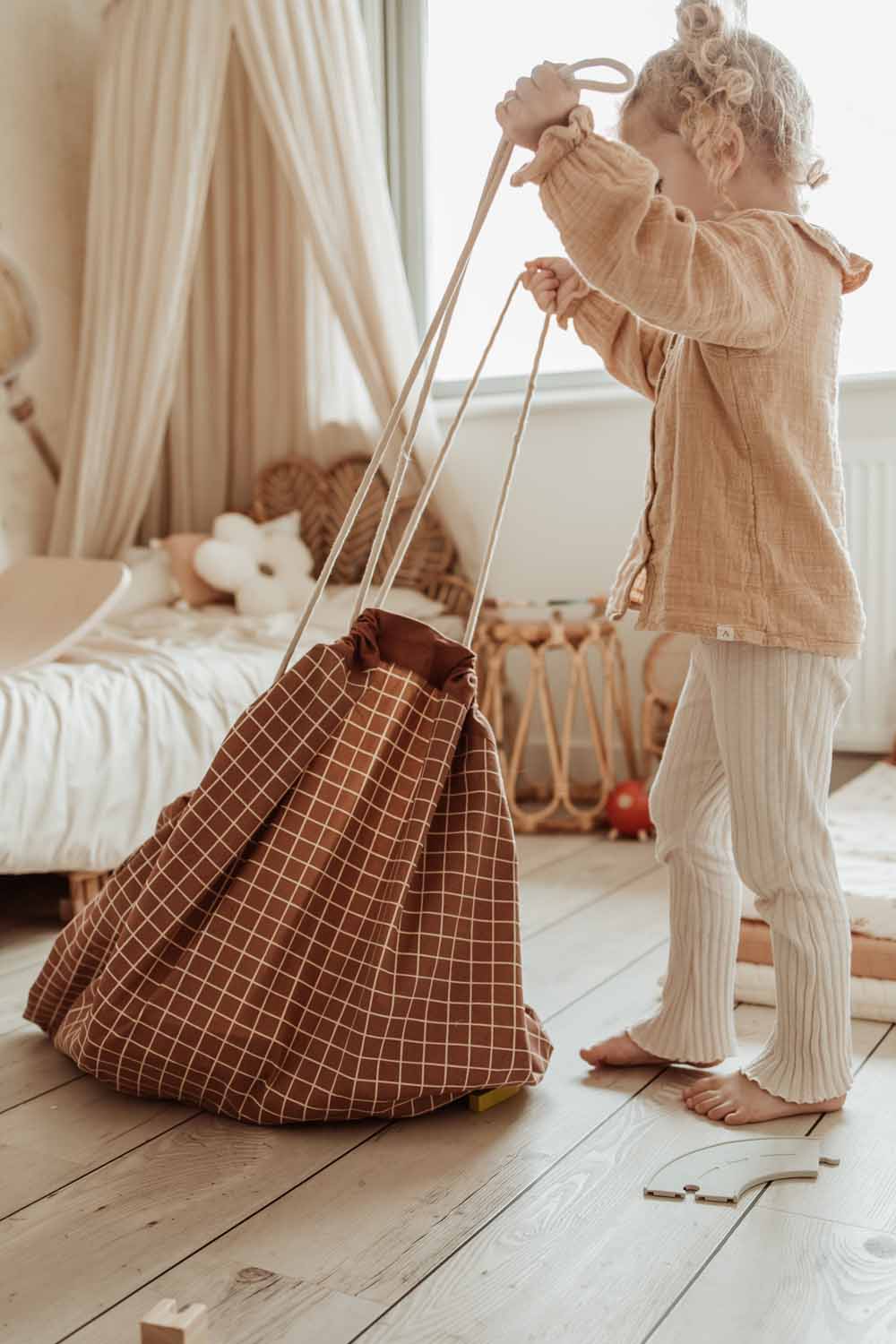 organic grid brown storage bag, child pulling the ropes, bag in kidsroom, next to bed