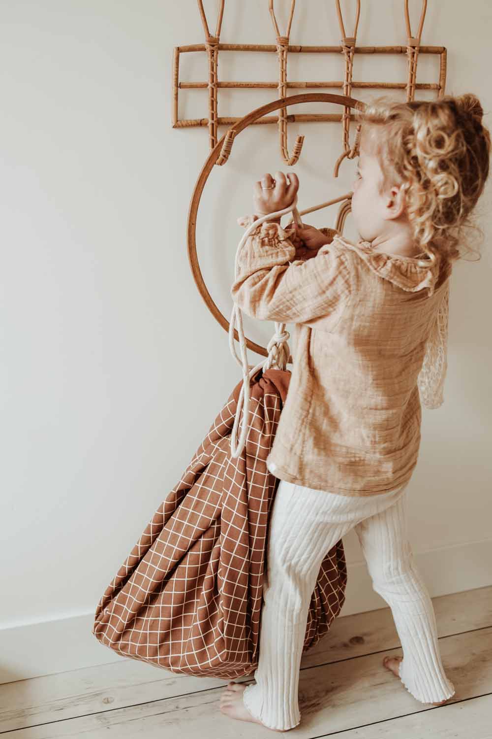 organic grid brown storage bag, child hanging closed bag on coatrack