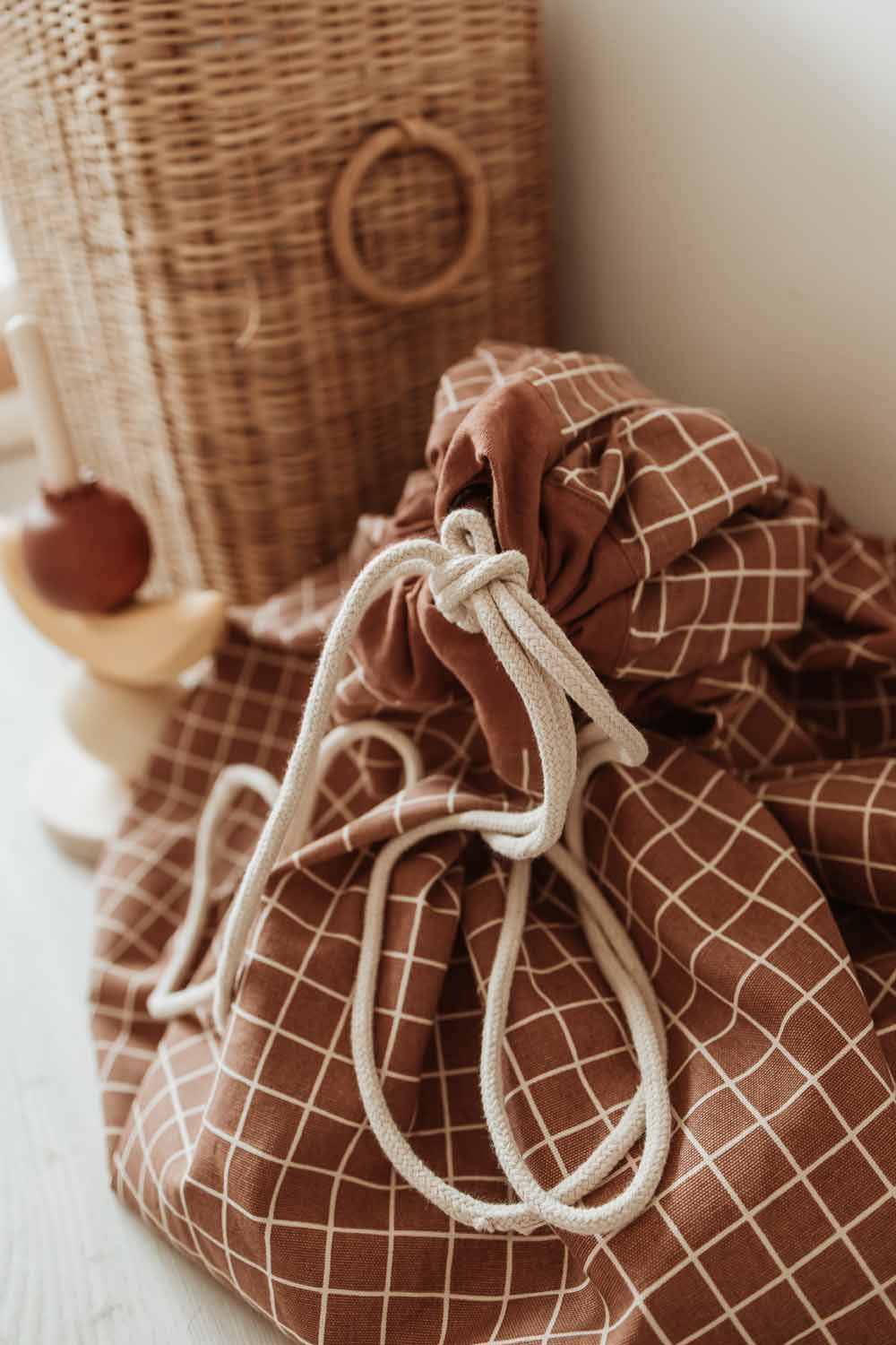 closed organic grid brown storage bag, next to wicker basket