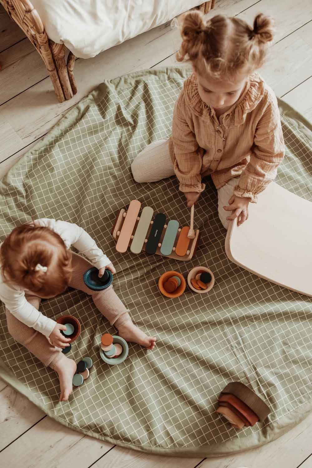 organic grid green storage bag, open on floor, children sitting on the mat, playing with wooden toys