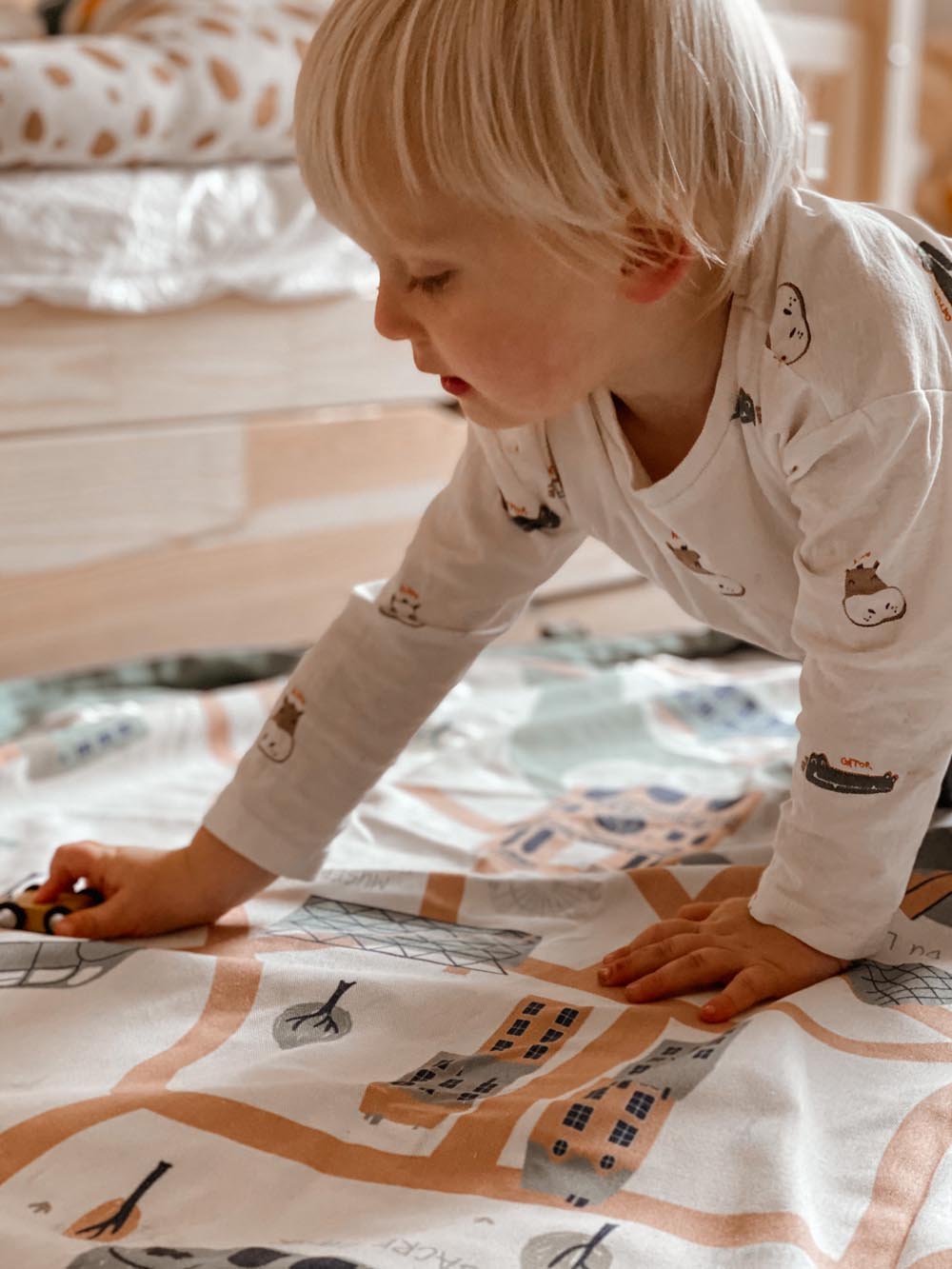 stylish designed Paris Map toy storage bag, child playing with little cars on open mat, in kidsroom next to bed