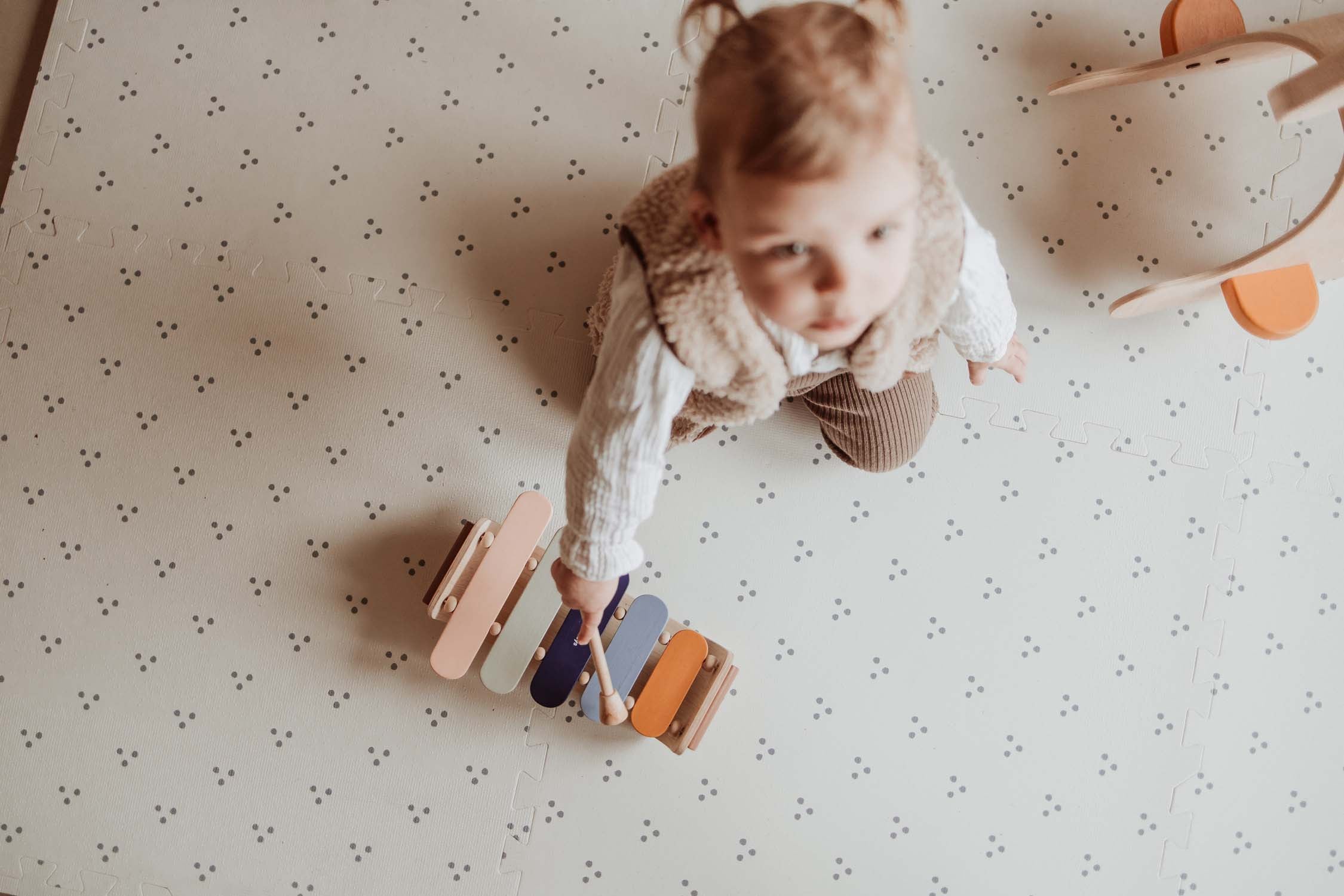 child playing with xylophone on dots puzzlemat